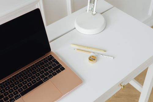 Free A clean, minimalist desk setup with a laptop, pens, and lamp, perfect for workspaces. Stock Photo