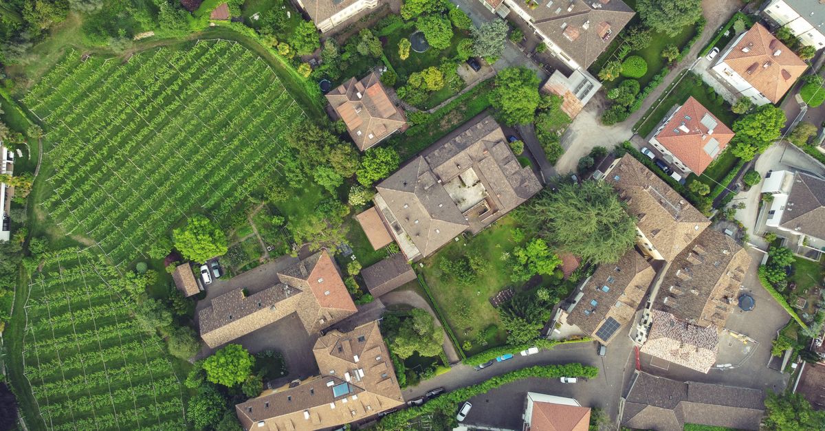 Aerial view showcasing residential buildings and lush vineyards in Bolzano, Italy.
