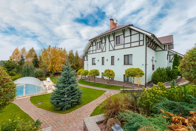 A timber-framed house with landscaped gardens and a pool. Photo by Max Vakhtbovych on Pexels.