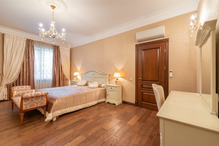 Bed, An Ottoman And A Vanity Table In A Hotel Room