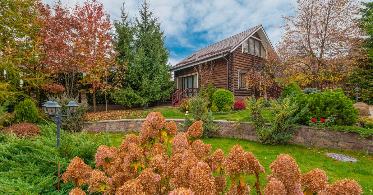 A picturesque log cabin surrounded by vibrant autumn foliage in a scenic garden setting.