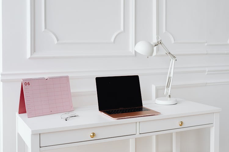 A Laptop And Desk Lamp On The Table 