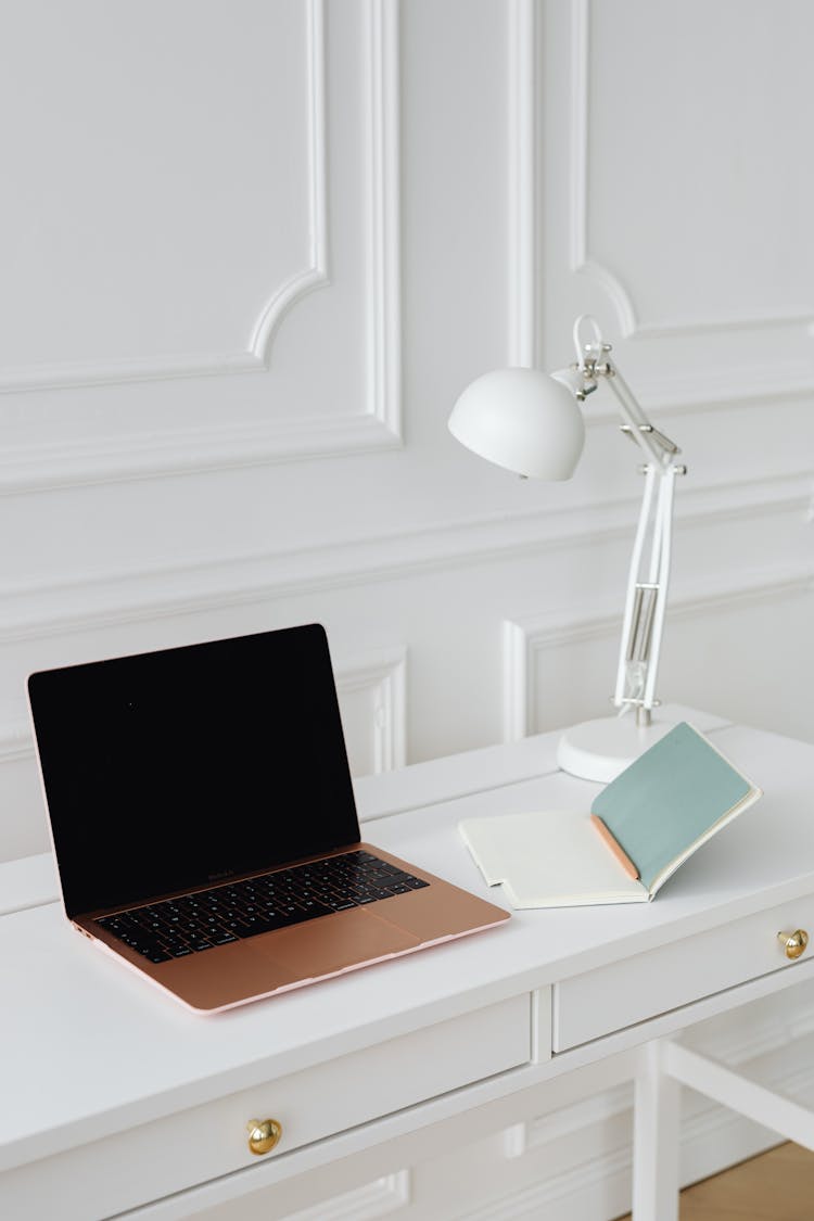 A Laptop And Desk Lamp On The Table