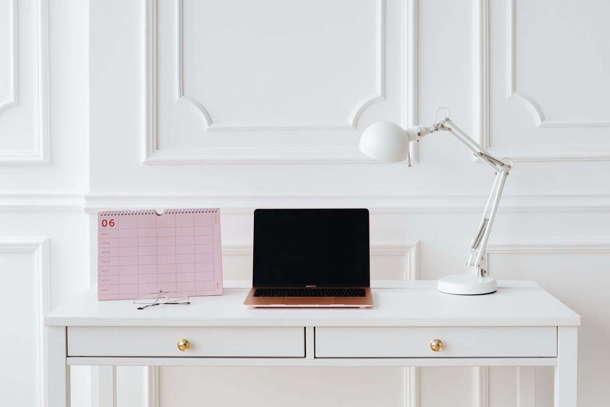 A laptop and desk calendar on a white table.