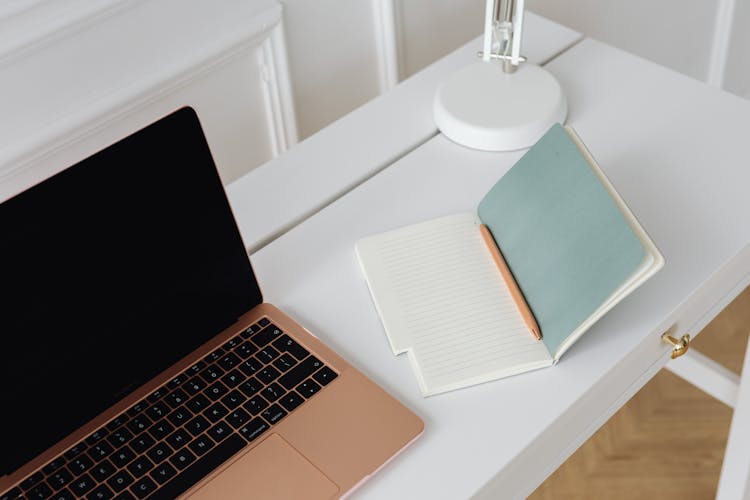 A Laptop And Notebook On The Table 