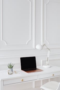 Modern minimalist desk setup featuring a laptop and white desk lamp for an elegant office design.