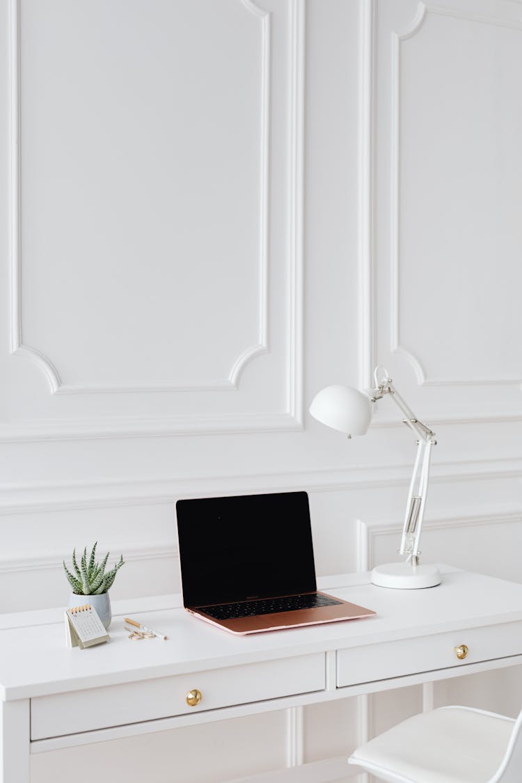 A Laptop And Desk Lamp On The Table 