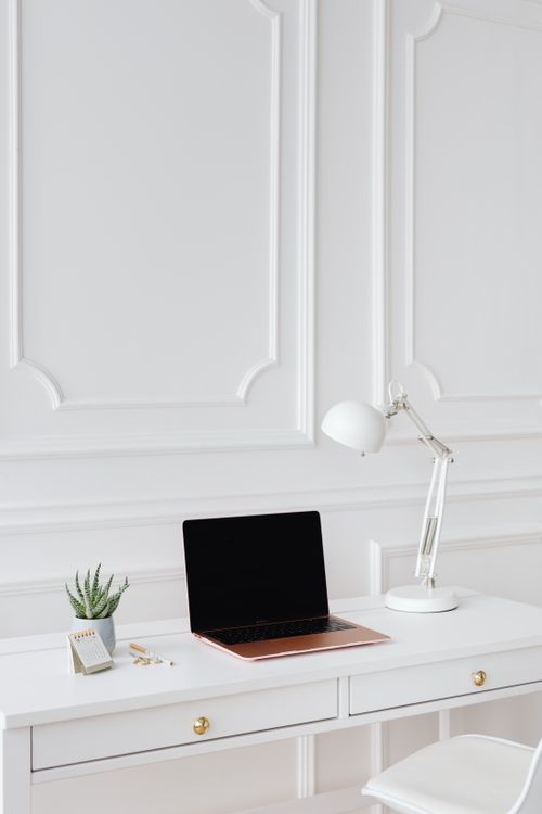 Free Modern minimalist desk setup featuring a laptop and white desk lamp for an elegant office design. Stock Photo