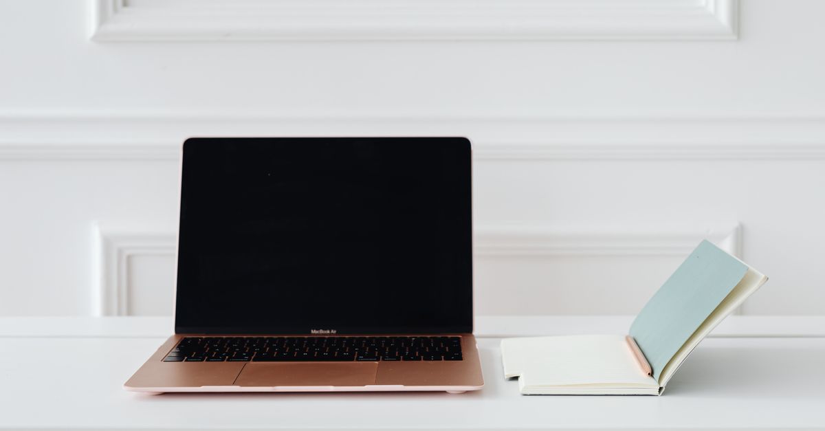 A clean, minimalist desk setup with a gold laptop and open notebook, perfect for productivity.