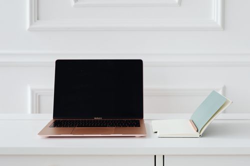Free A clean, minimalist desk setup with a gold laptop and open notebook, perfect for productivity. Stock Photo