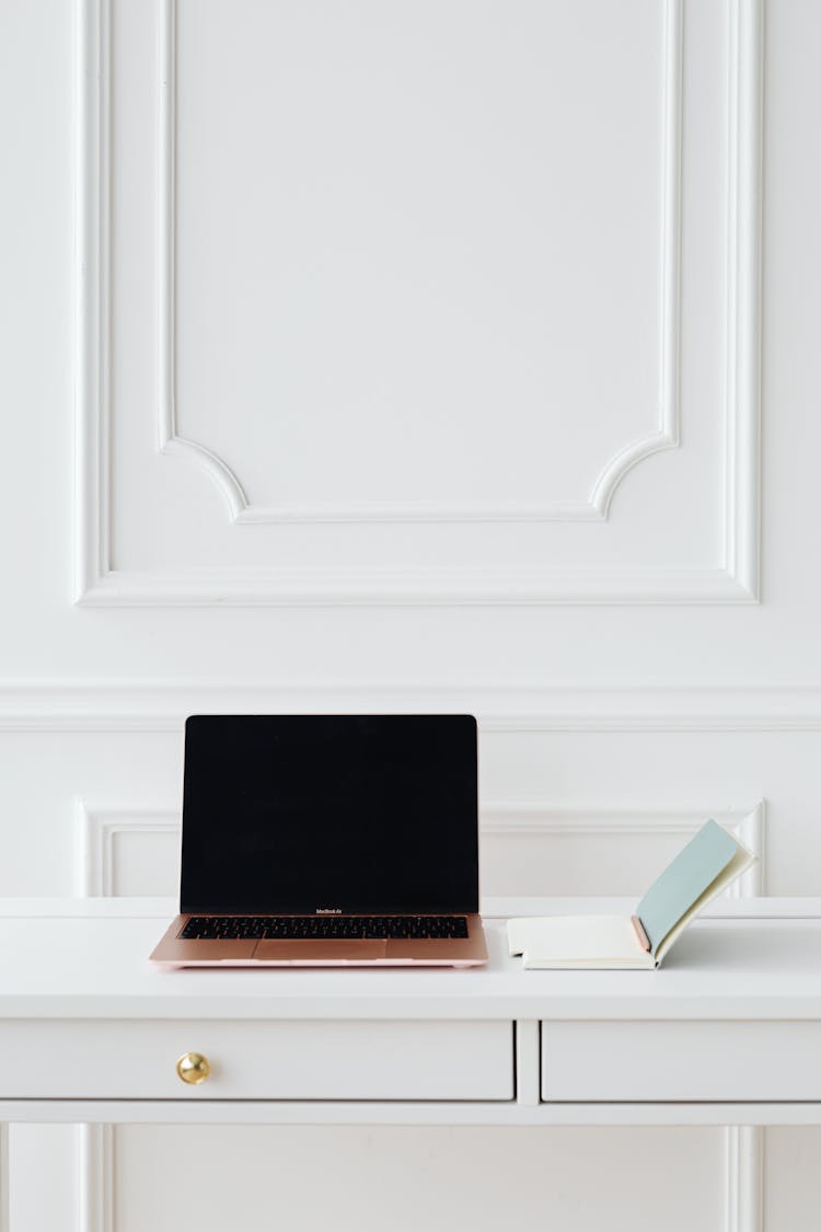 A Notebook And A Laptop On A Desk 