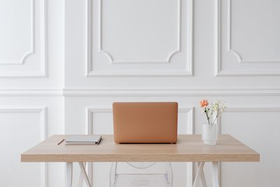 Laptop on a light wooden desk against a panelled wall — photo by Kaboompics on Pexels