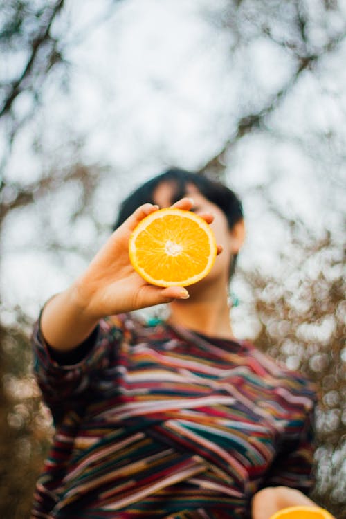 Person Holding a Slice of Orange Fruit