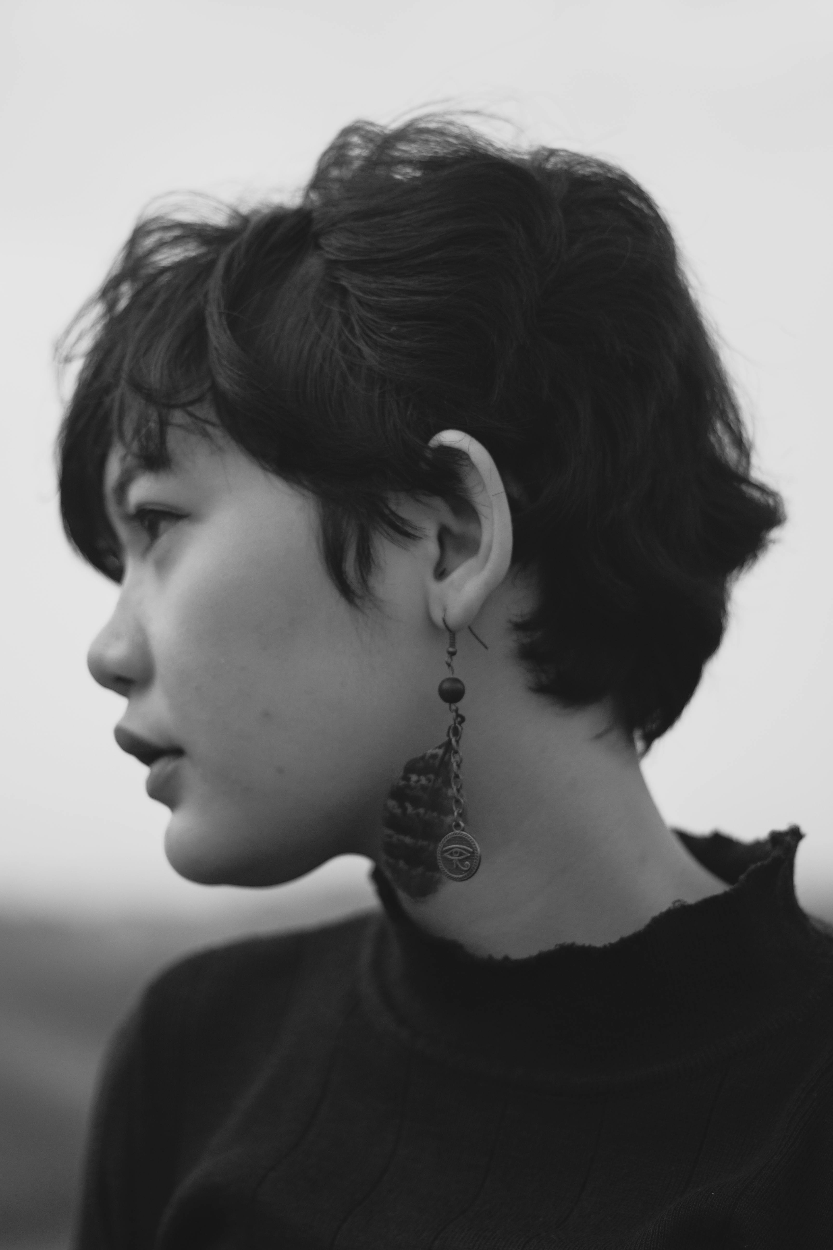 Artistic black and white portrait of a woman with short hair and earrings.