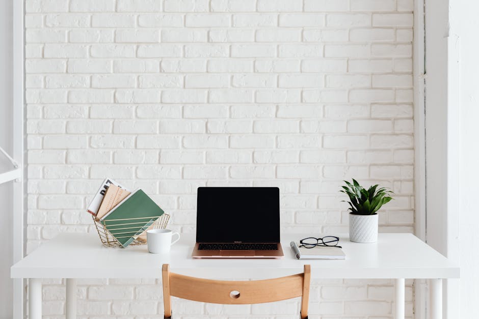 Laptop on White Desk Beside White Brick Wall