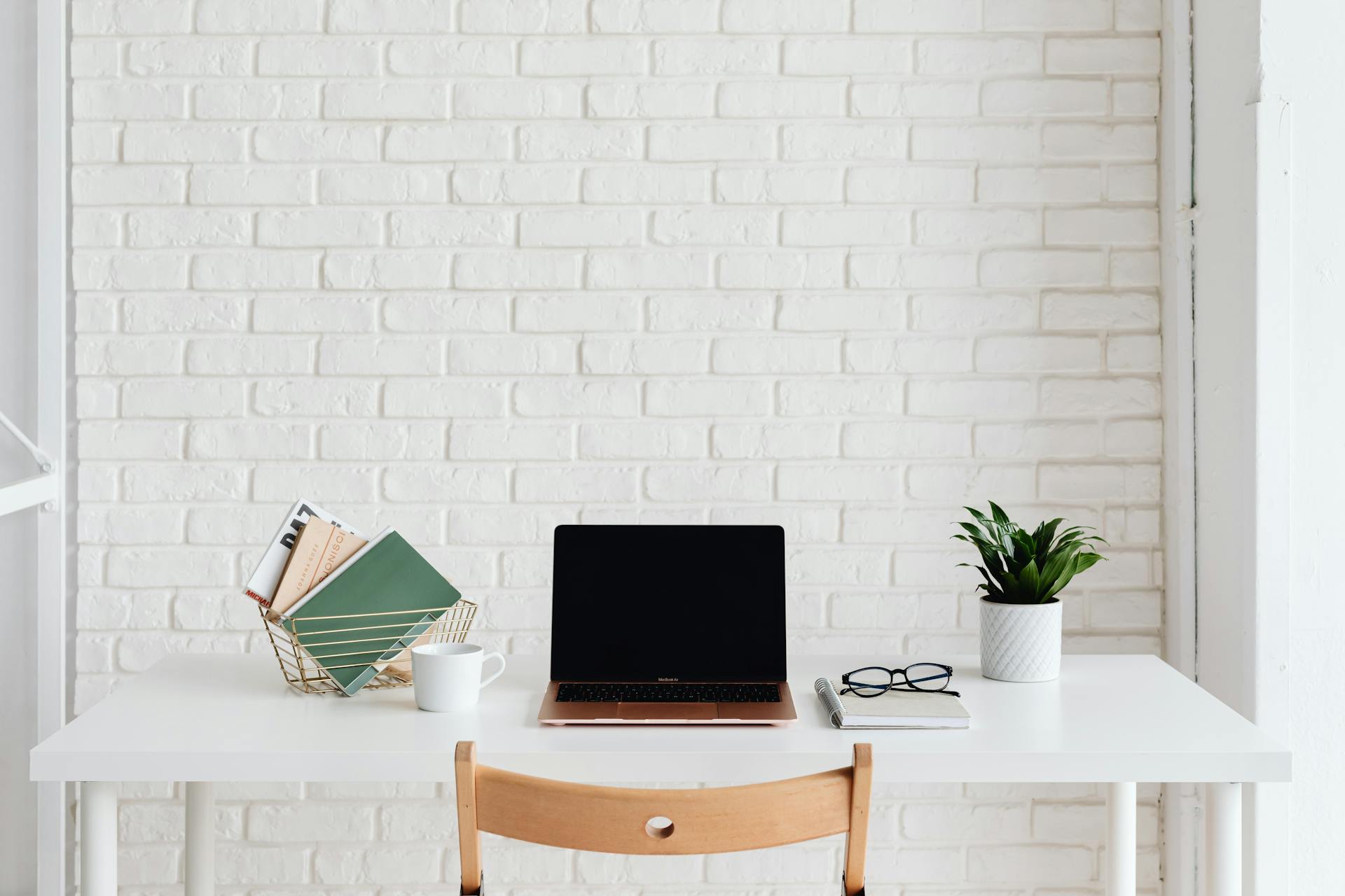 Laptop on White Desk Beside White Brick Wall