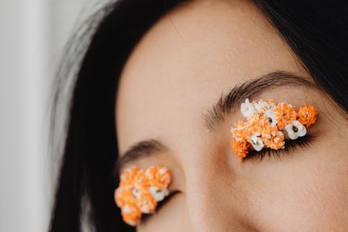 Free Close-up portrait featuring delicate floral art on eyelashes, blending beauty with creativity. Stock Photo