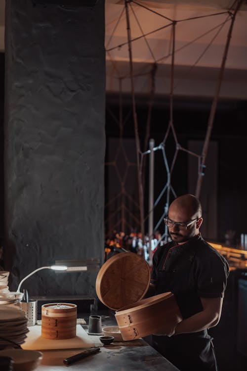 Man in Black Chef Shirt Holding Bamboo Steamer Basket