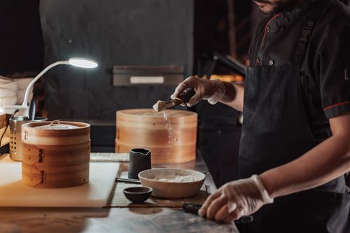 Free A chef skillfully prepares ingredients using a bamboo steamer in a well-lit kitchen. Stock Photo