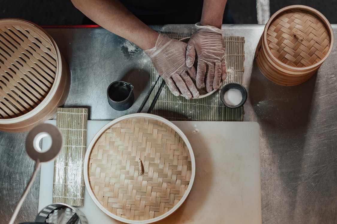 Free Person in Gloves Cooking on the Table Beside Bamboo Baskets Stock Photo