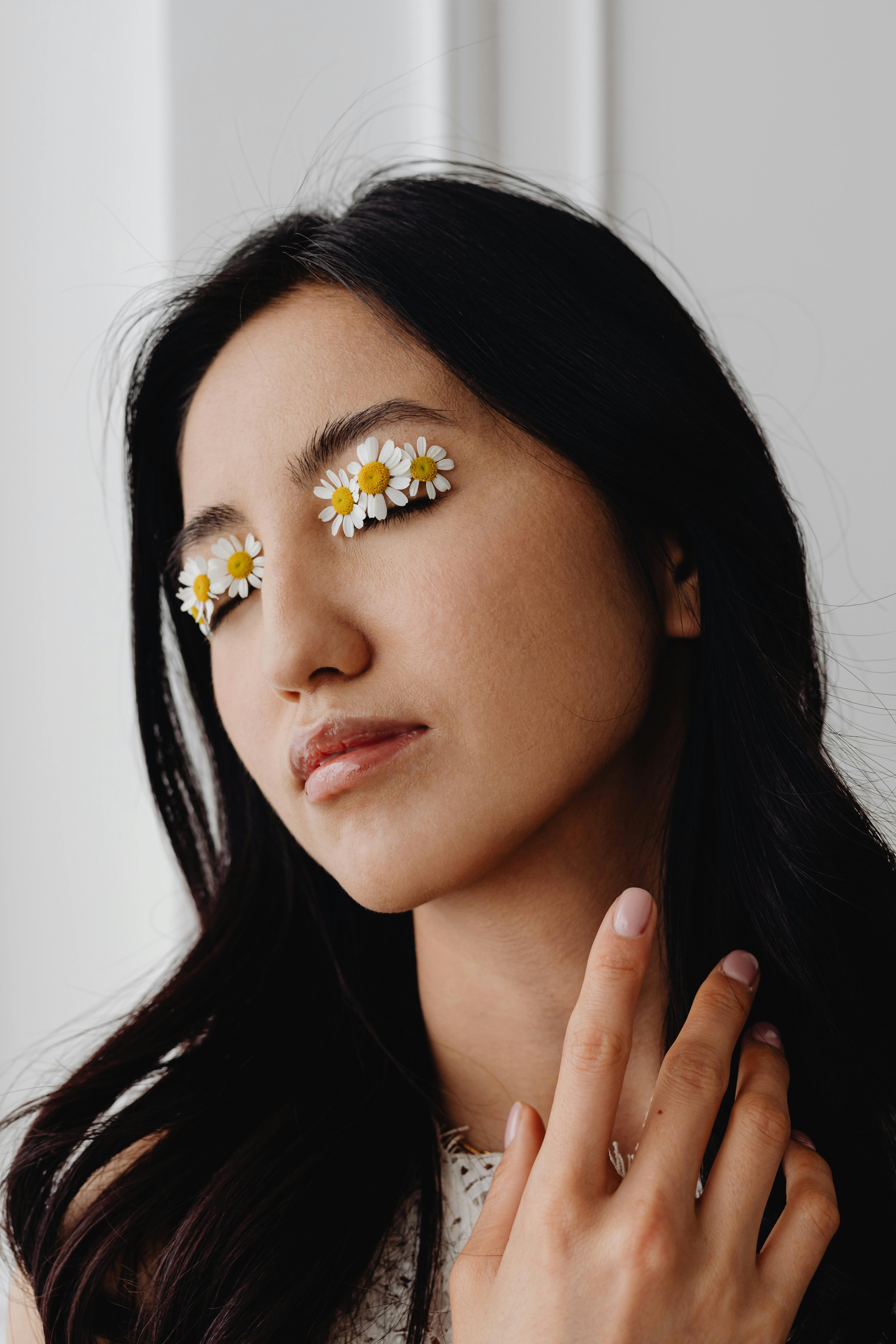 Close-up portrait of a woman with creative flower eyelid makeup. Simplistic fashion statement.