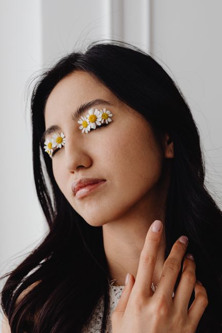 Close-up portrait of a woman with creative flower eyelid makeup. Simplistic fashion statement.