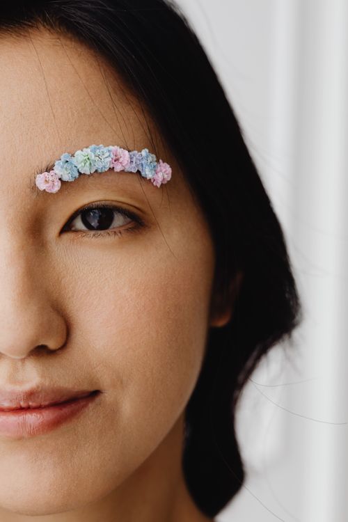 Free Close-up portrait of a woman with creative floral eyebrow makeup, showcasing art and individuality. Stock Photo