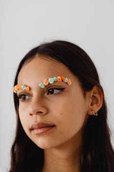 Unique portrait of a young woman with artistic floral eyebrows against a white background.