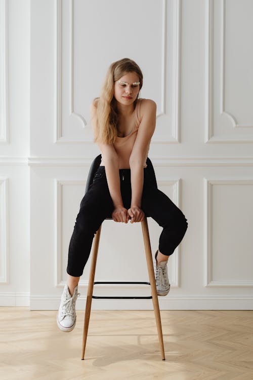 Young Woman in Black Pants Sitting on Wooden Stool
