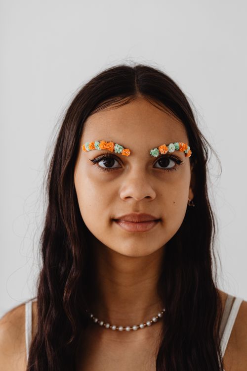Free Close-up portrait of a girl with unique floral eyebrow decorations on a white background. Stock Photo