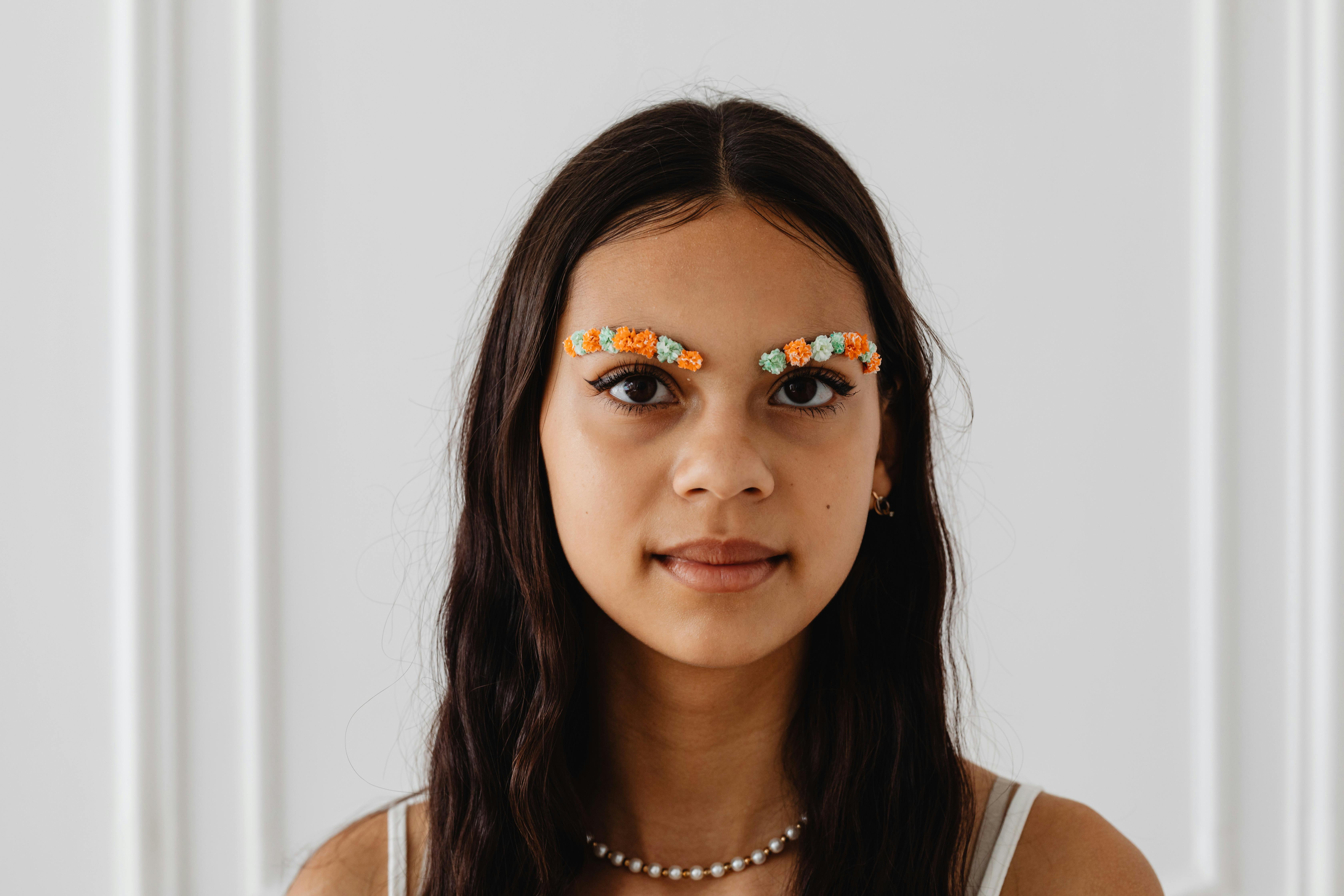 Portrait of a woman with artistic floral eyebrows and natural expression.