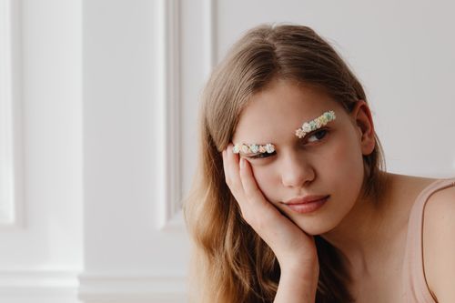 Free Creative portrait of a woman with floral eyebrows, offering a blend of nature and beauty indoors. Stock Photo