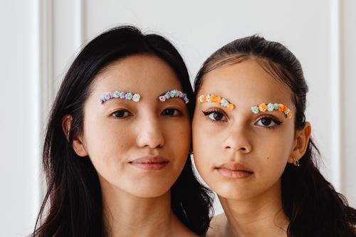 Free Creative close-up portrait featuring floral eyebrow decorations on two models indoors. Stock Photo