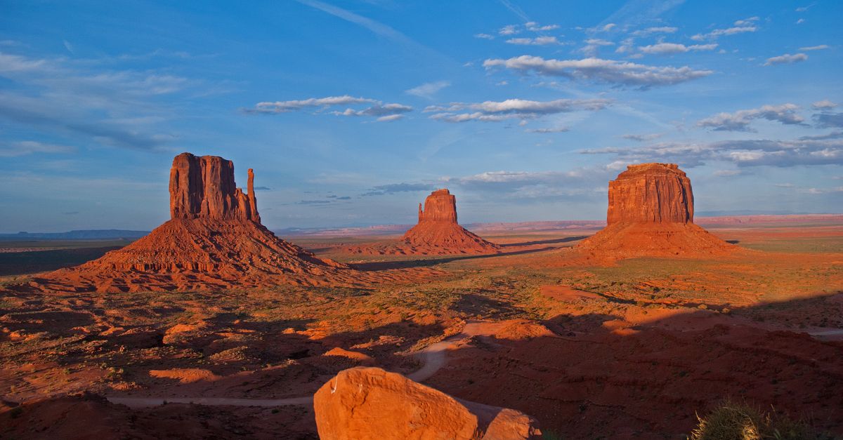 Stunning view of Monument Valley's iconic buttes under a vibrant sunset sky, capturing the grandeur of the natural landscape.