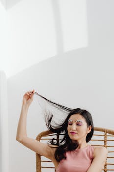 A serene woman with vibrant eye makeup relaxes in a sunlit room, creating a peaceful atmosphere.