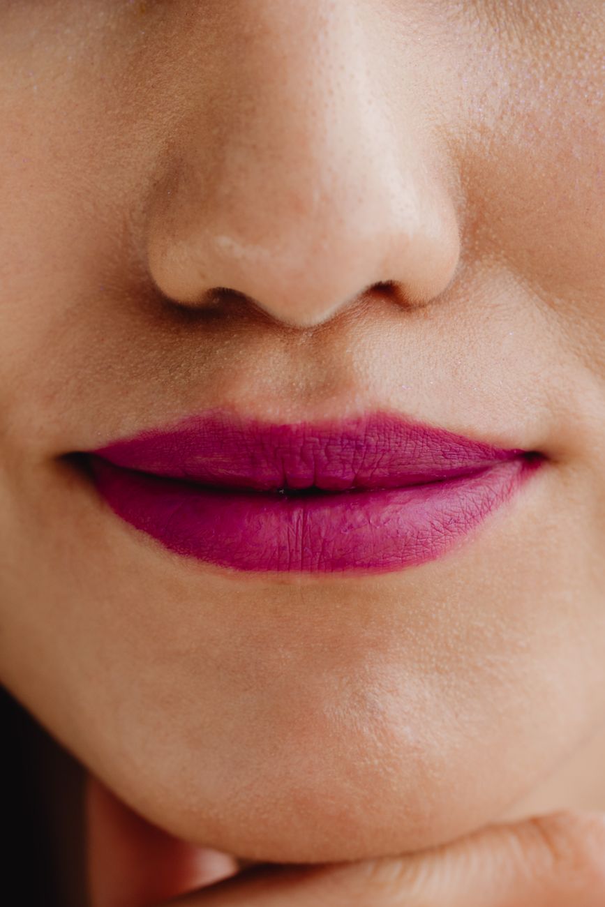 A detailed close-up of bright lips and smooth skin, used here to underline the care-language beauty brands attach to make-up products.