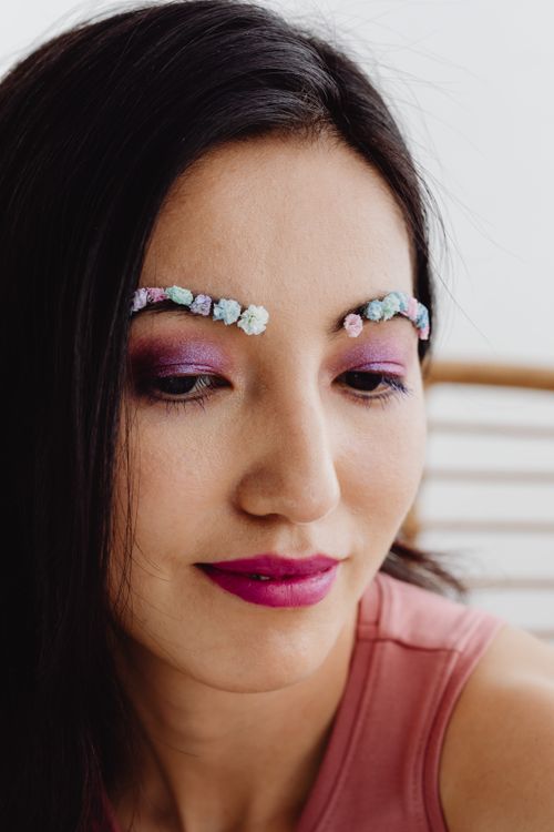 Free Close-up portrait of a woman with floral makeup and vibrant eyeshadow and lipstick. Stock Photo
