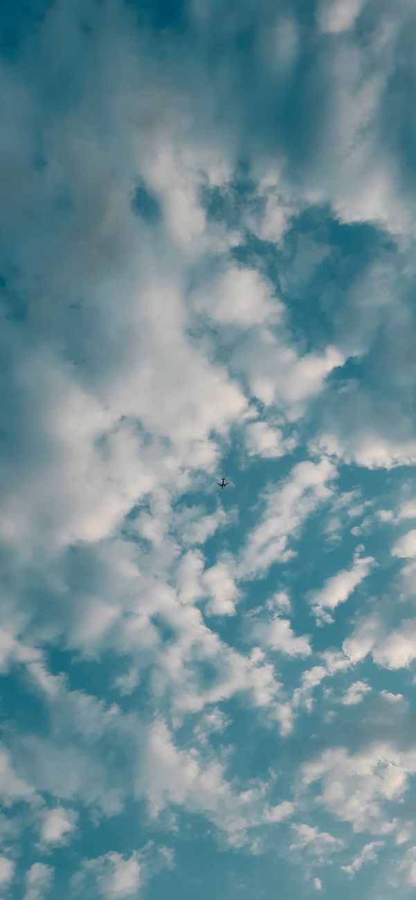 Abstract background of from below of fluffy white clouds floating in blue sky in daytime