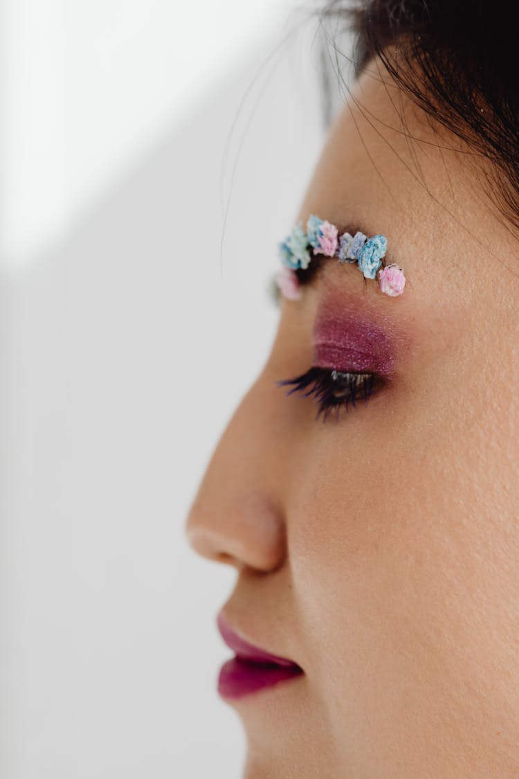 Close-Up Photo Of A Woman With Glitter Eye Makeup And Flower Brow