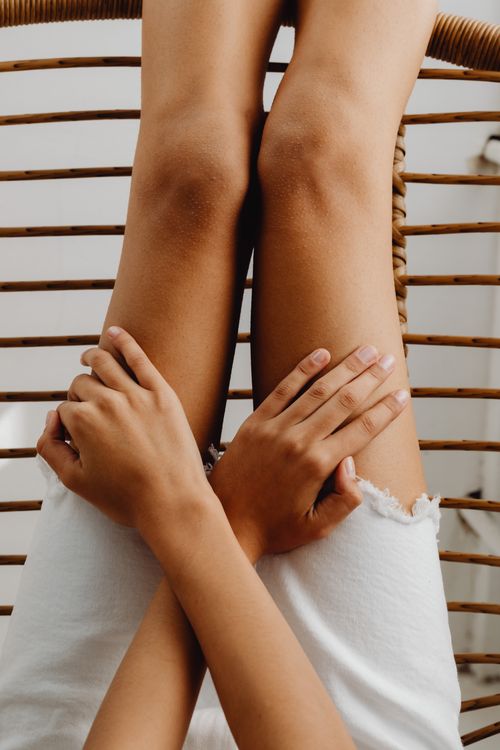 Free Close-up of hands resting on knees while lounging in a hammock, enjoying a sunny day. Stock Photo