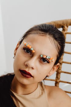 Portrait of a woman with vibrant floral designs on her eyebrows, showcasing creative makeup artistry.