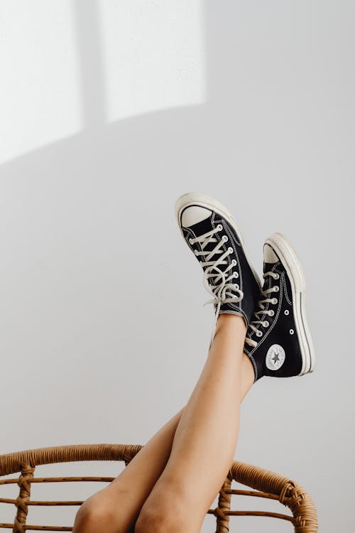 A Person Wearing Black and White Converse All Star High Top Sneakers