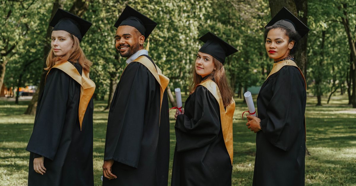 Photo by olia danilevich A celebratory group of diverse graduates wearing caps and gowns outdoors, holding diplomas.