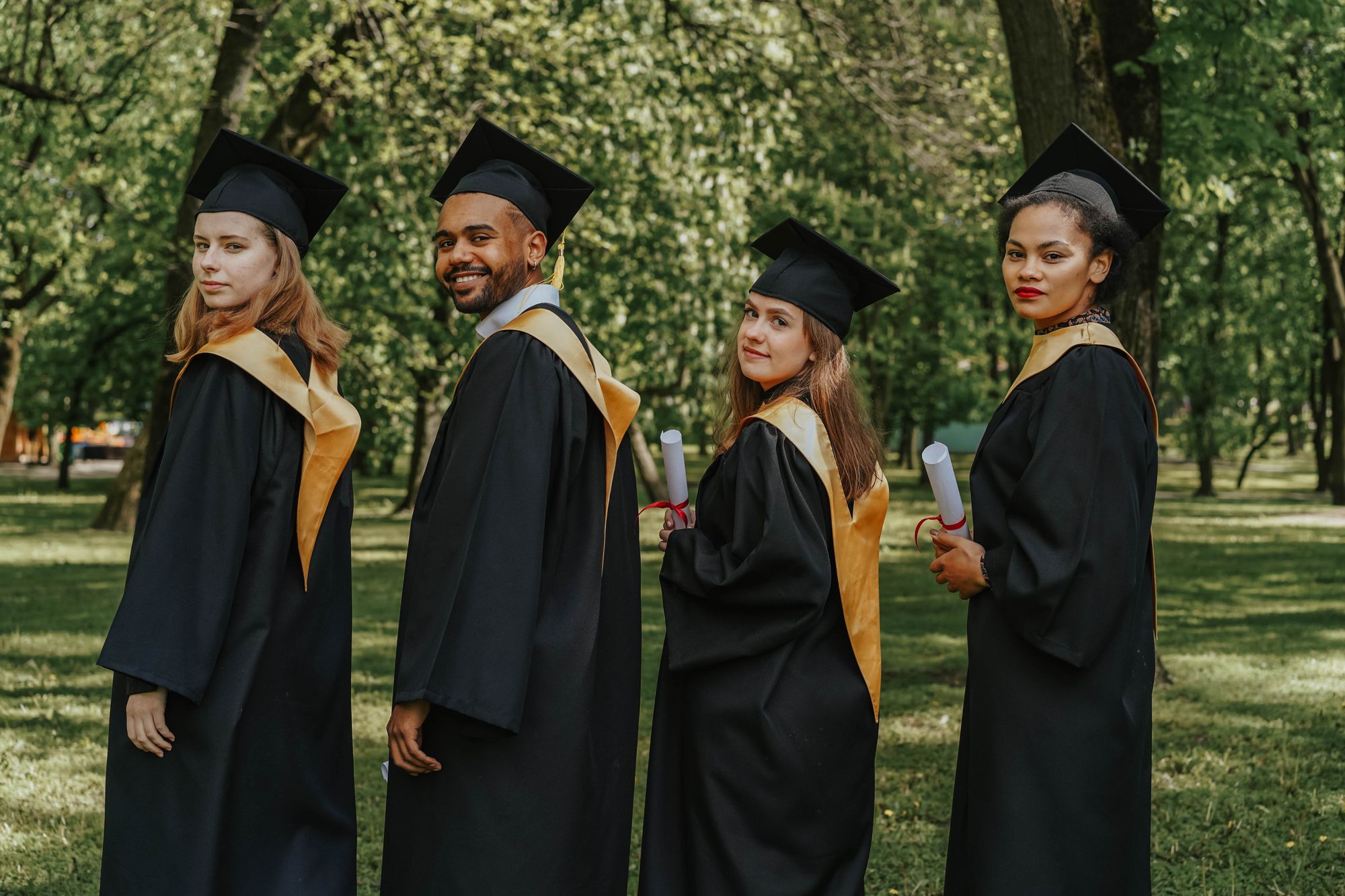 Graduates wearing caps and gowns holding diplomas at a convocation ceremony