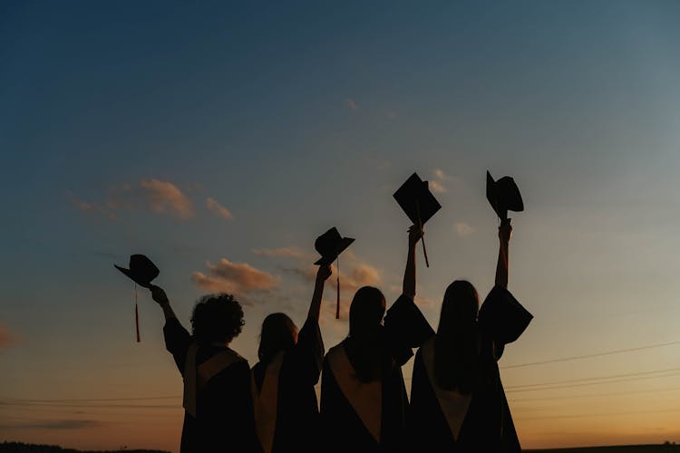 Silhouette Of People Raising Their Graduation Hats