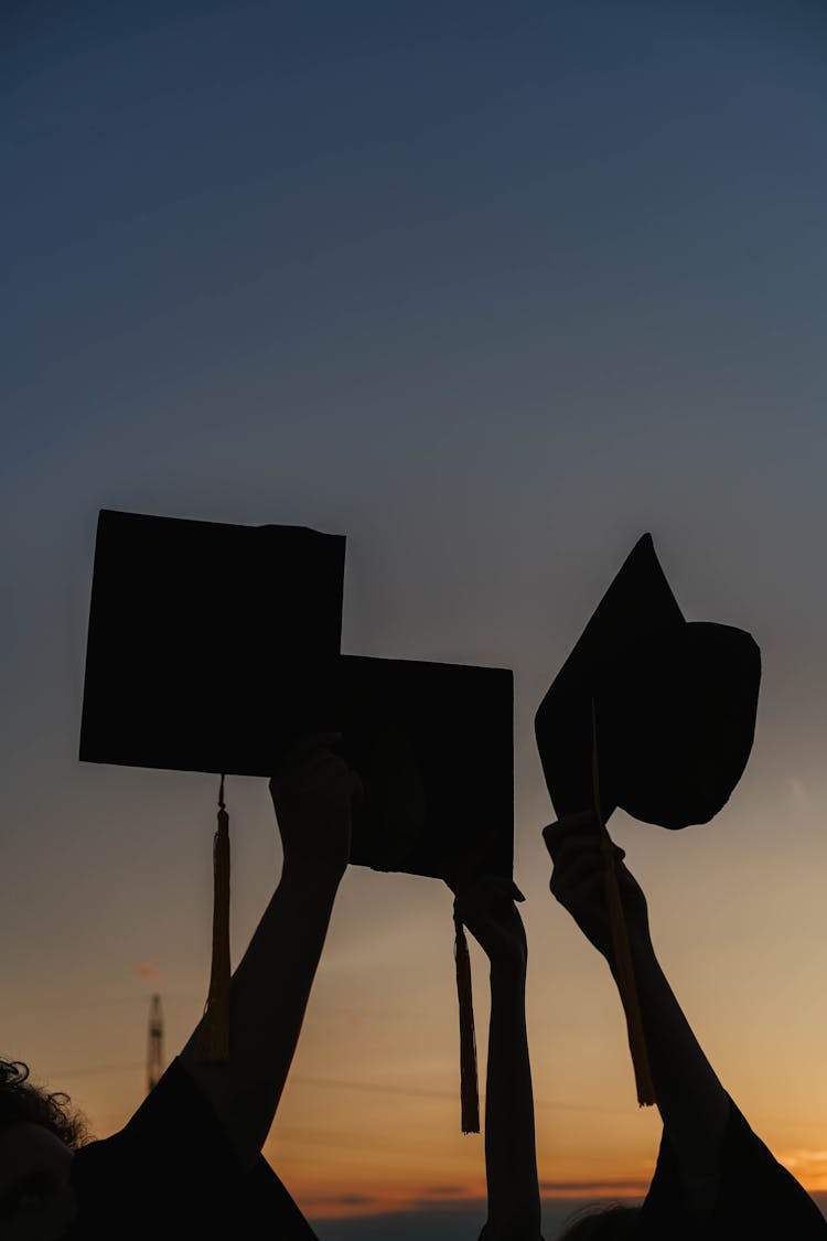 Silhouette Of People Holding Graduation Caps