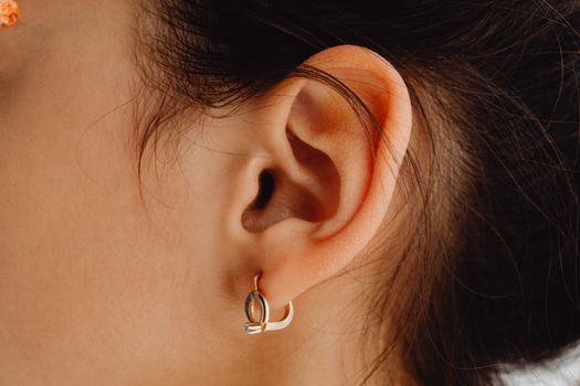 Detailed close-up of a woman's ear adorned with a stylish earring.