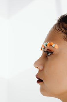 Artistic side profile of a woman with delicate floral eyebrow design on a white background.