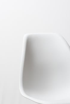 A minimalist white chair on a plain background, showcasing modern design.