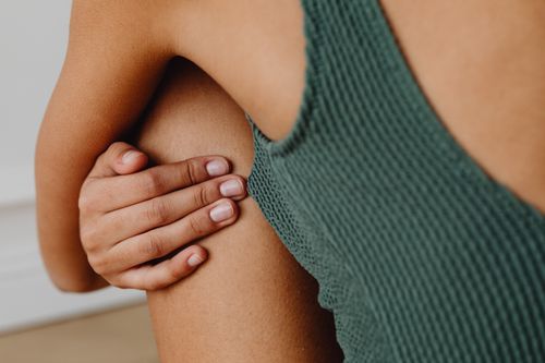 Free A close-up of a person's hand gently resting on their knee in a minimalist, intimate setting. Stock Photo